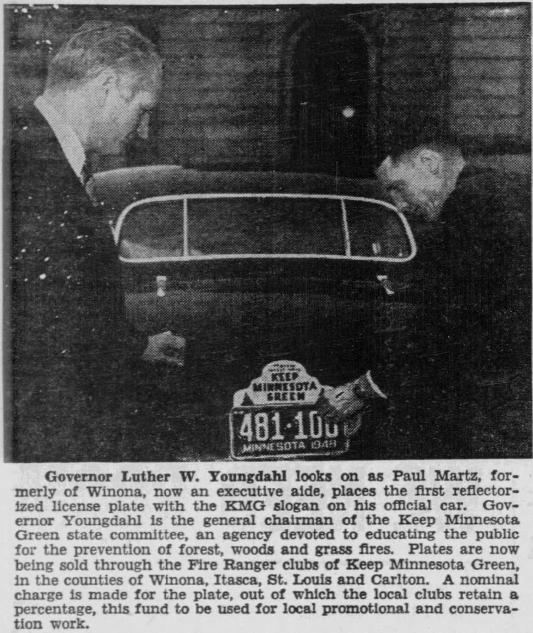 Newspaper photo of Governor Luther W Youngdahl attaching a Keep Minnesota Green license plate topper to his car in 1948